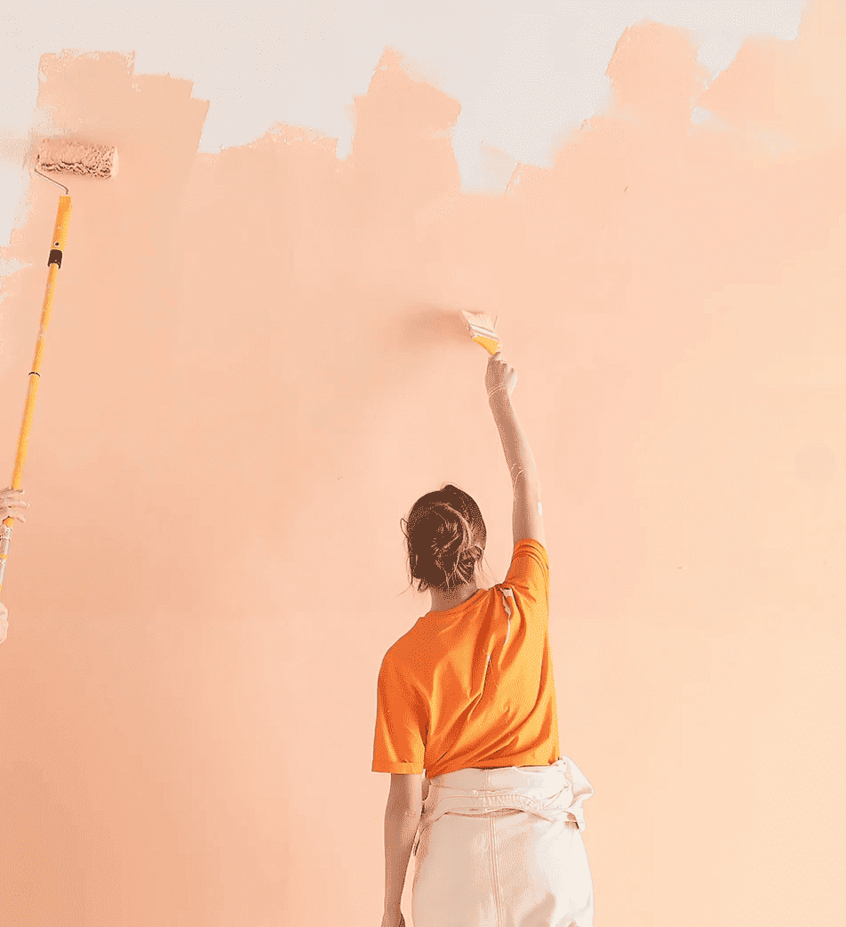 Mujer aplicando pintura color melocotón sobre pared interior.
