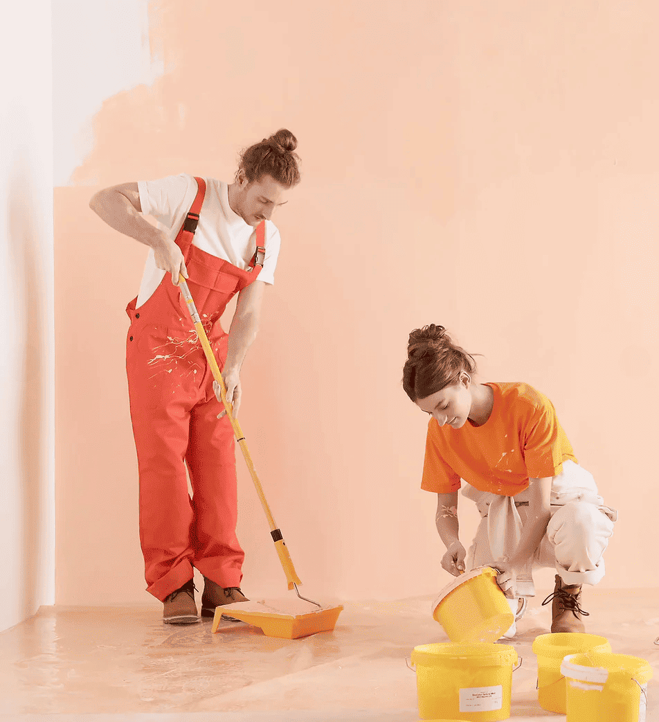 Pareja pintando habitación con pintura clara.