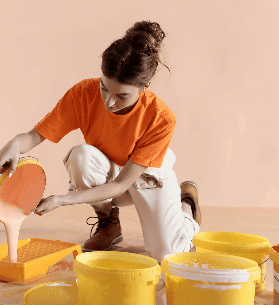 Mujer vertiendo pintura en bandeja con cubos amarillos alrededor.