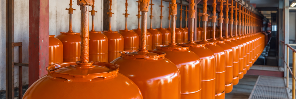 Botellas de gas pintadas en color naranja durante una prueba de aplicación de pintura industrial de Dekoin 98 en Sevilla.